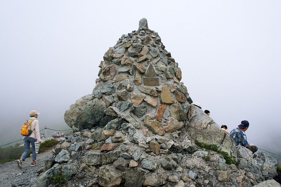 Cairn at Happo-ike pond on Happo-one ridge with Northern Alps behind