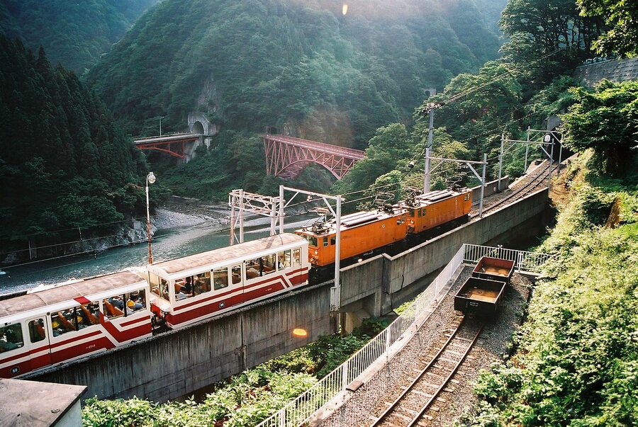 Kurobe Gorge Railway open carriage on a stone bridge above the gorge