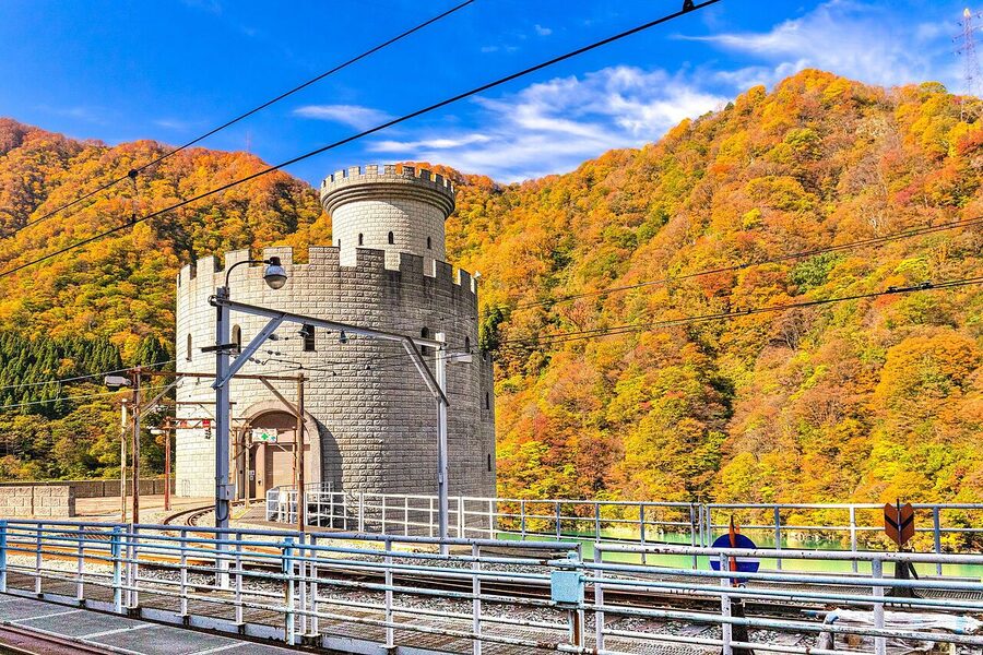 Kurobe Gorge Railway open-sided carriage running through autumn foliage