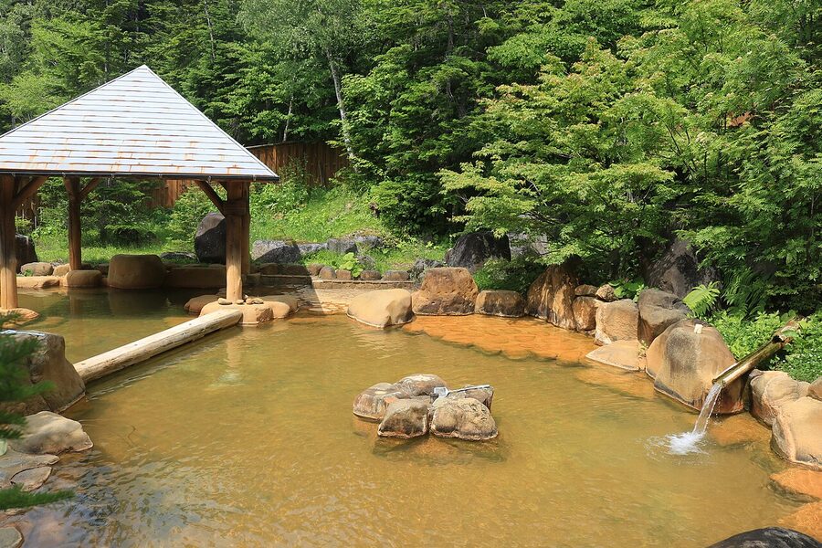 Milky-white outdoor onsen pool with mineral deposits on the rim